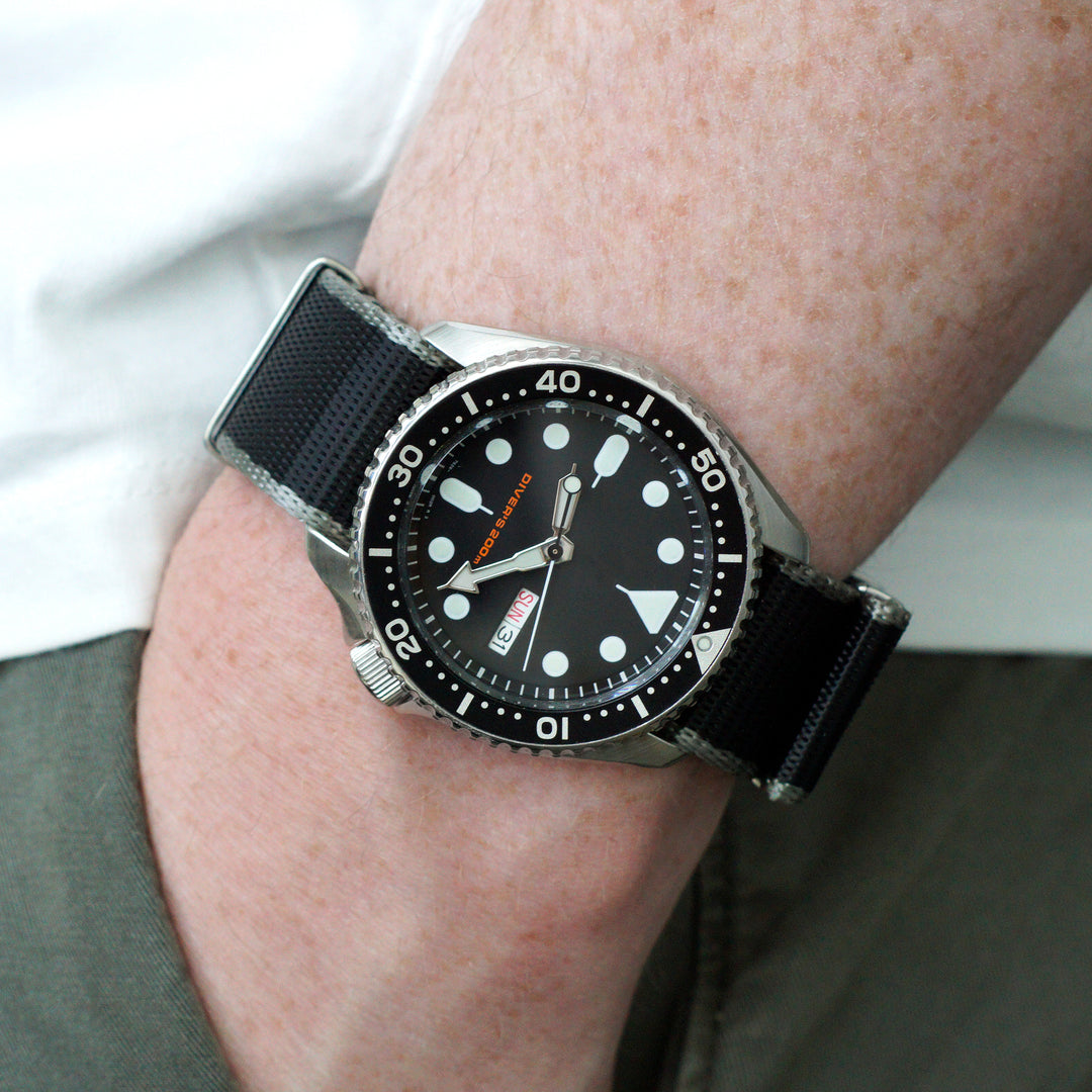 Black wristwatch with a detailed face on a person's wrist #color_black-with-grey-edge