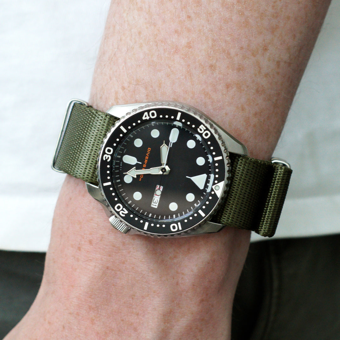 Watch with a green strap on a wrist against a neutral background #color_army-green