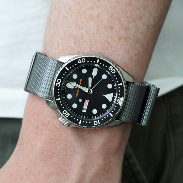 Wrist wearing a watch with a black face and silver band. #color_grey