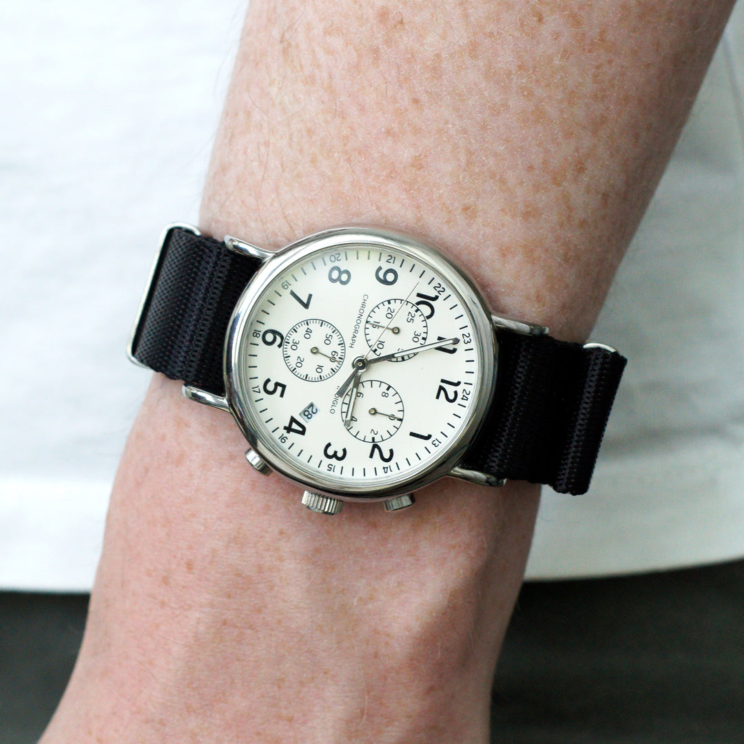 Wrist wearing a watch with a black strap and white face. #color_black