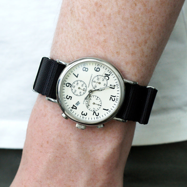 Wrist wearing a watch with a black strap and white face. #color_black