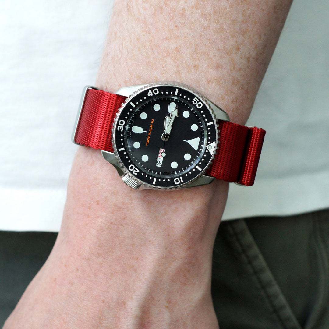 Wrist wearing a watch with a red strap on a neutral background #color_red
