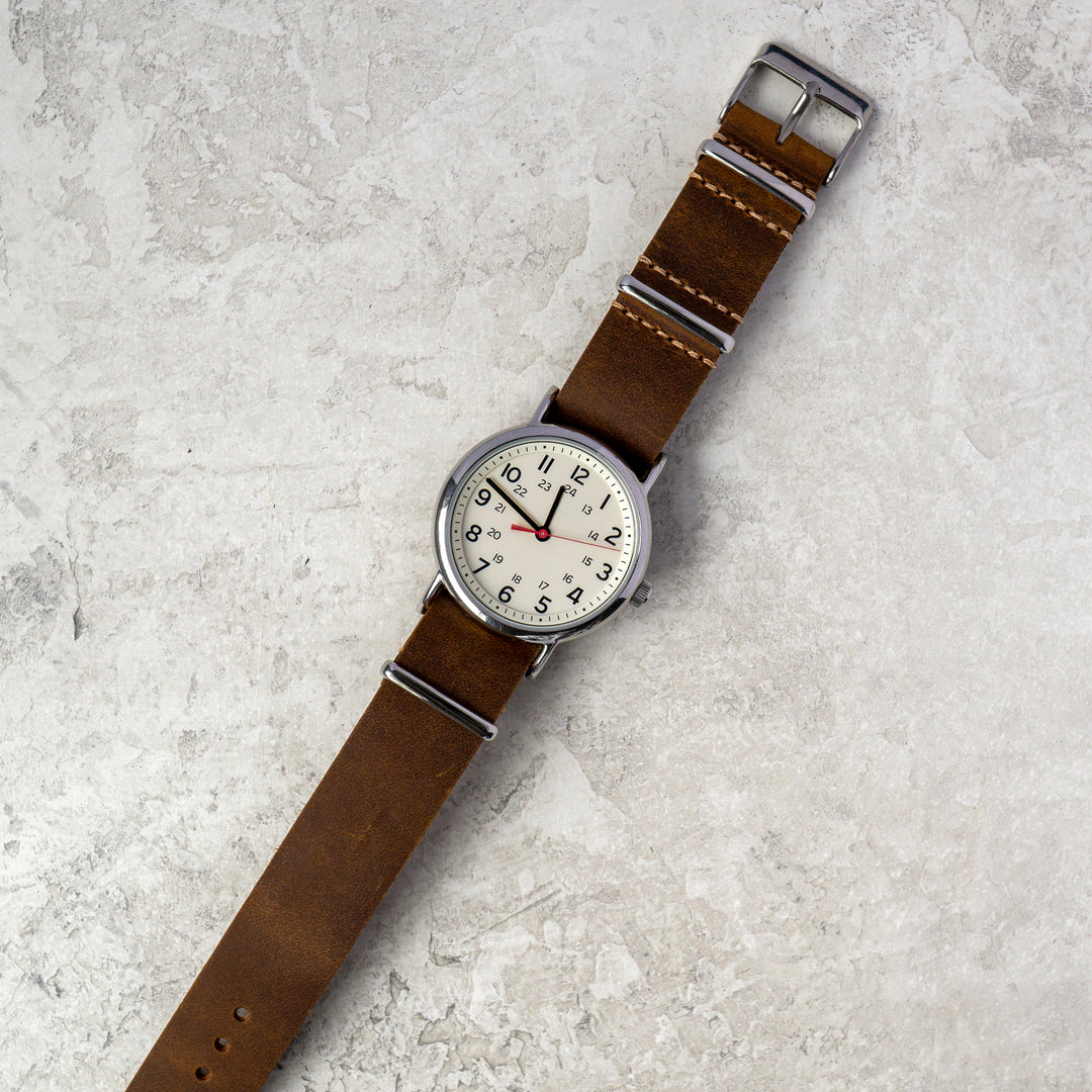 Watch with a brown strap on a textured gray surface #color_dark-brown