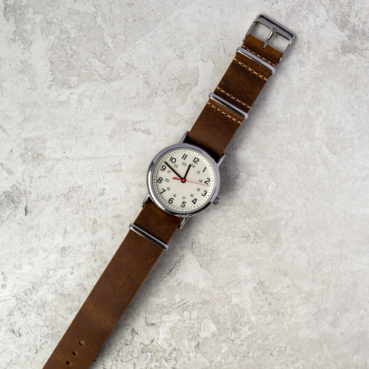 Watch with a brown strap on a textured gray surface #color_dark-brown