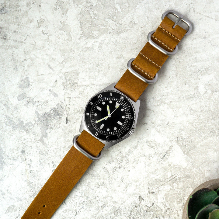 Watch with a brown leather strap on a textured gray surface #color_sand