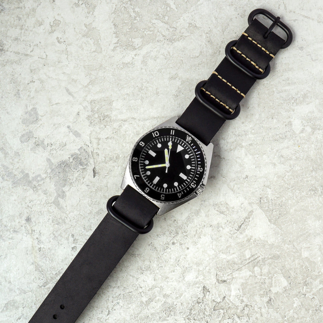 Black wristwatch with a textured strap on a light gray surface #color_black-pvd