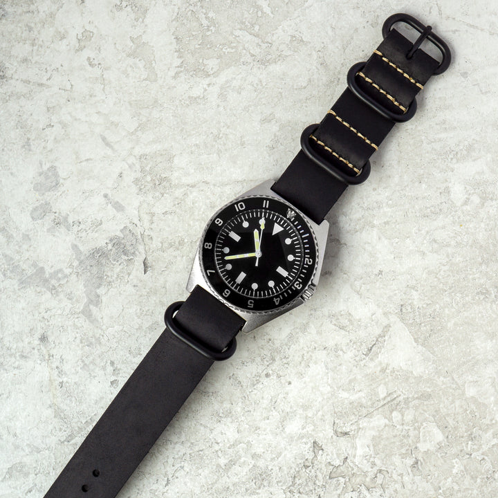 Black wristwatch with a textured strap on a light gray surface #color_black-pvd
