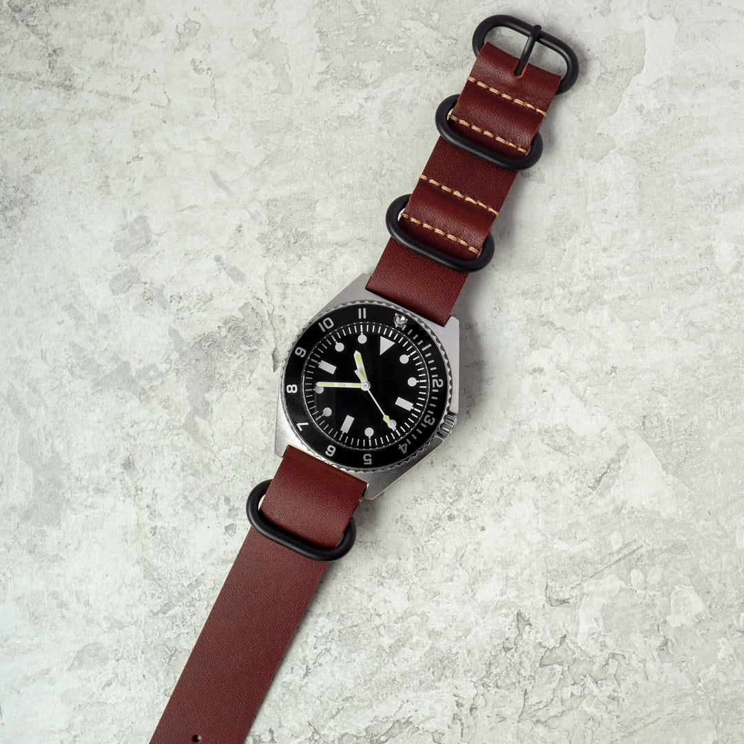Watch with a brown leather strap on a light gray surface #color_oxblood-pvd