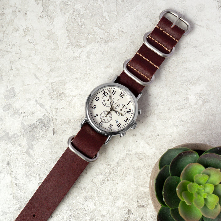 Watch with a red leather strap on a light gray surface with a succulent plant. #color_oxblood