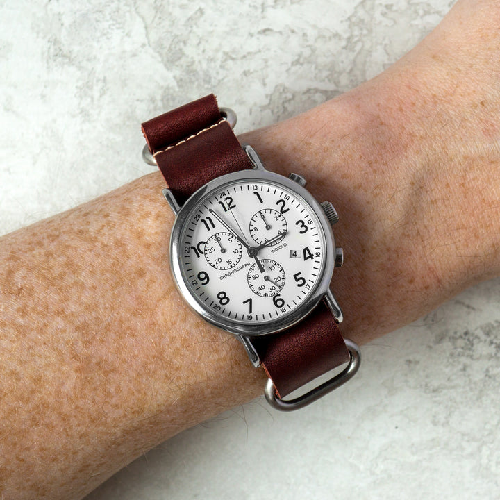 Watch with red leather strap on a wrist against a light background #color_oxblood