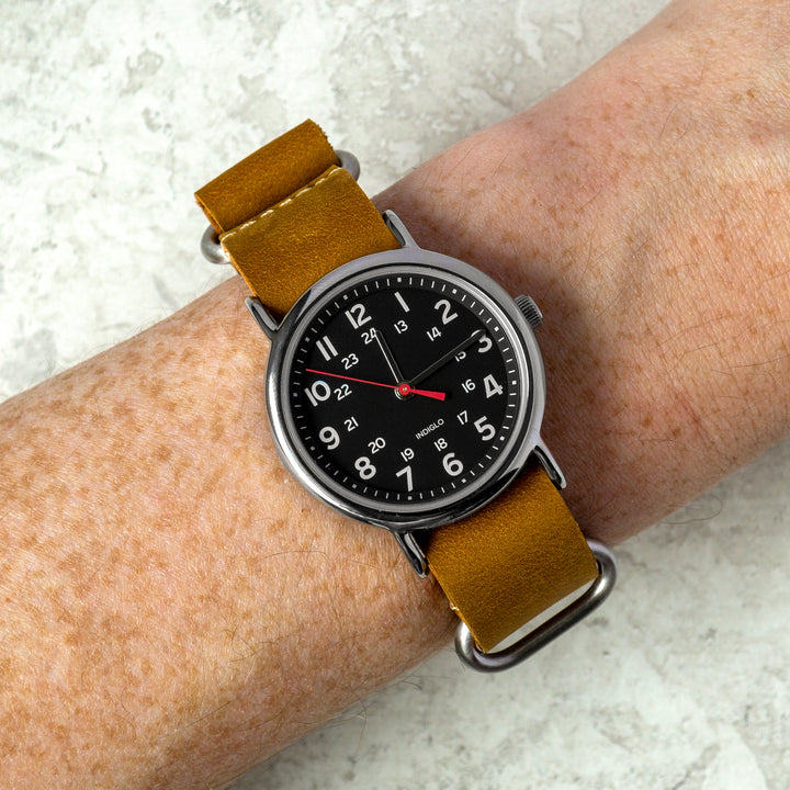 Watch with a brown leather strap on a wrist against a light background #color_sand