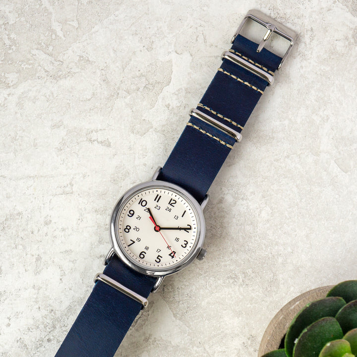Wristwatch with blue strap and silver case on a textured surface #color_navy-blue