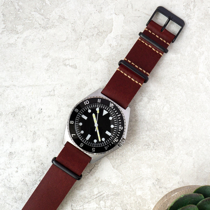 Watch with a red leather strap on a textured white surface #color_oxblood-pvd