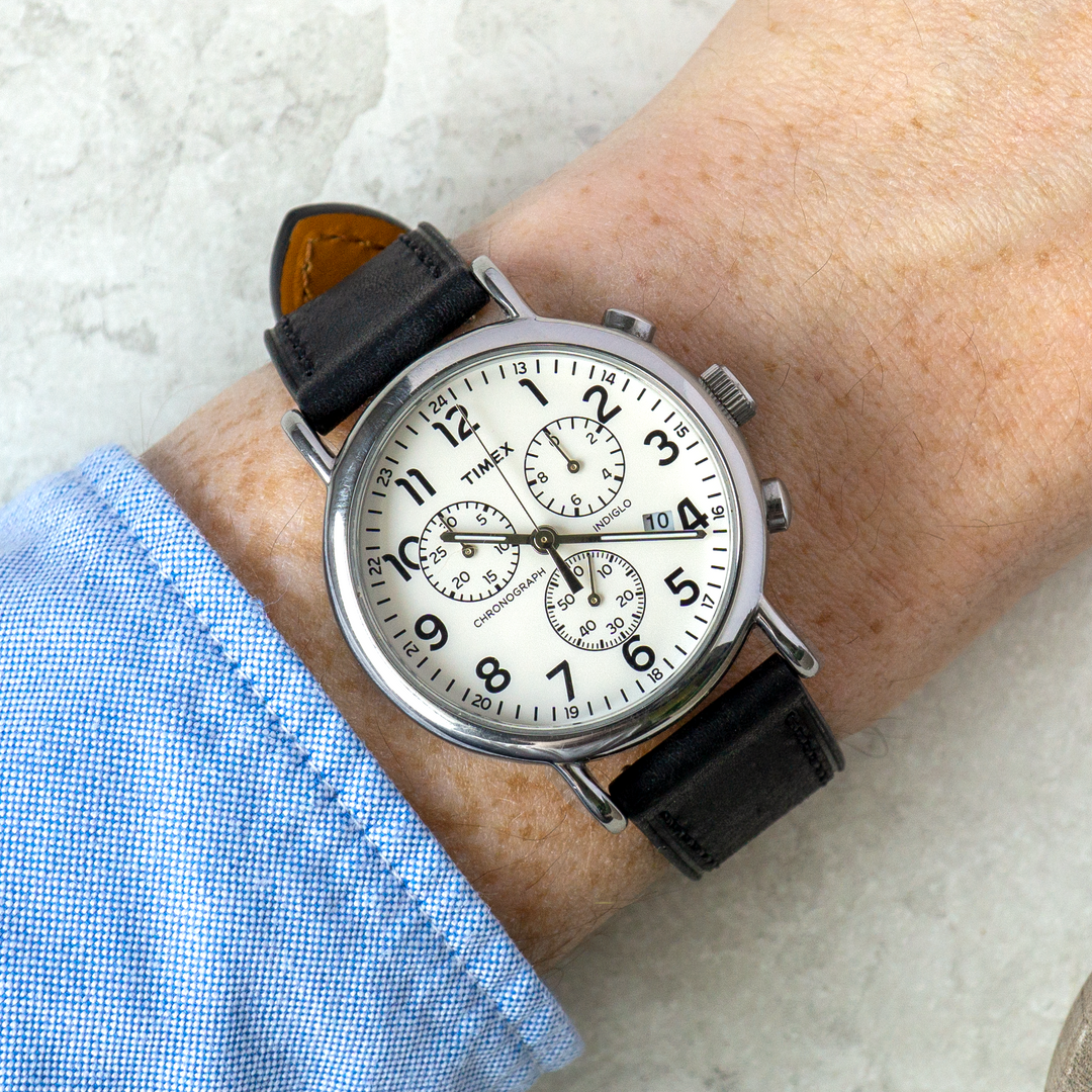 Wristwatch with black leather strap and silver case on a wrist, light background #color_black