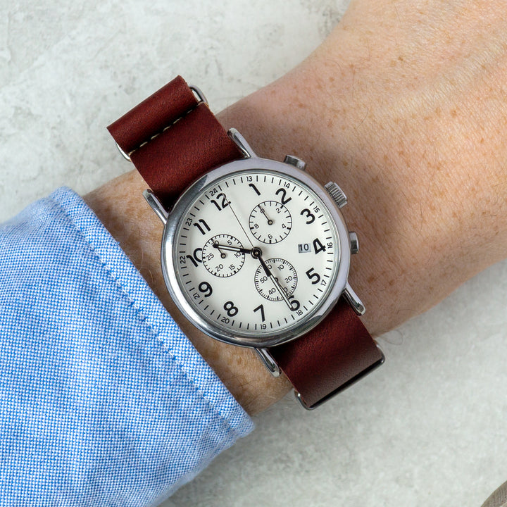 Wrist wearing a watch with a red leather strap on a light background #color_oxblood