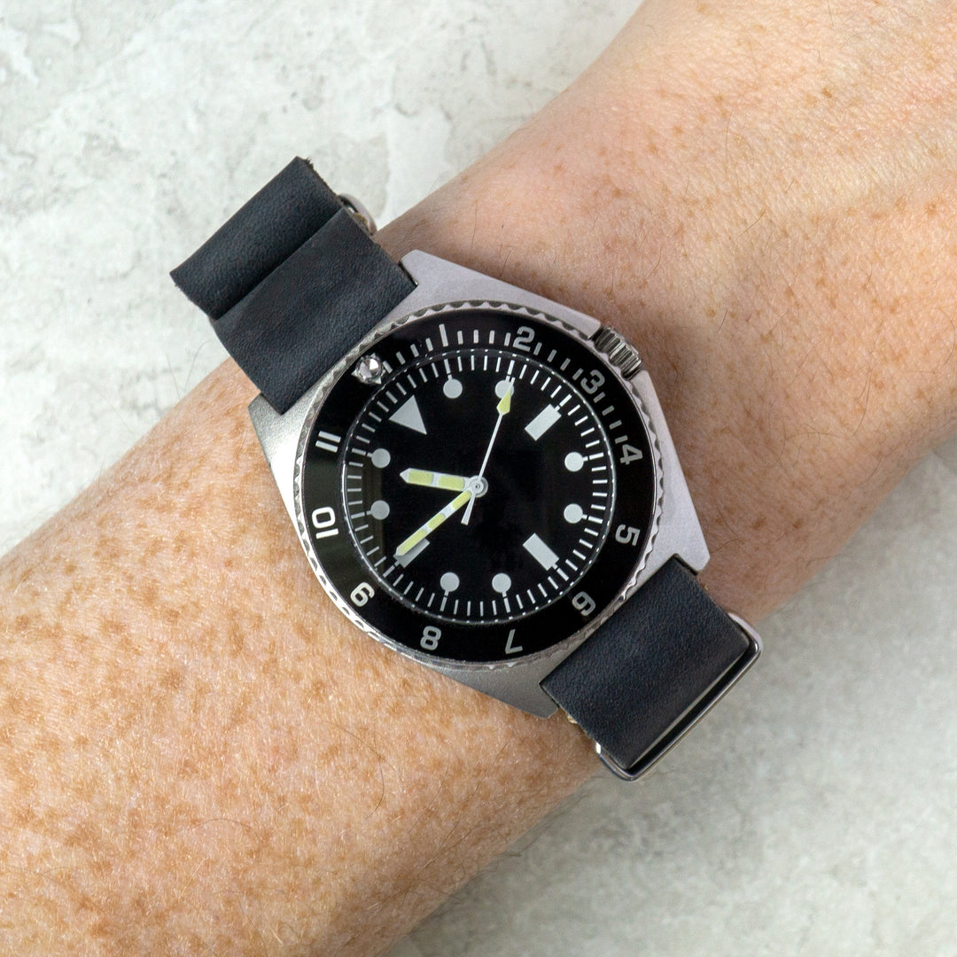 Wrist wearing a grey watch with a black strap on a light background #color_grey