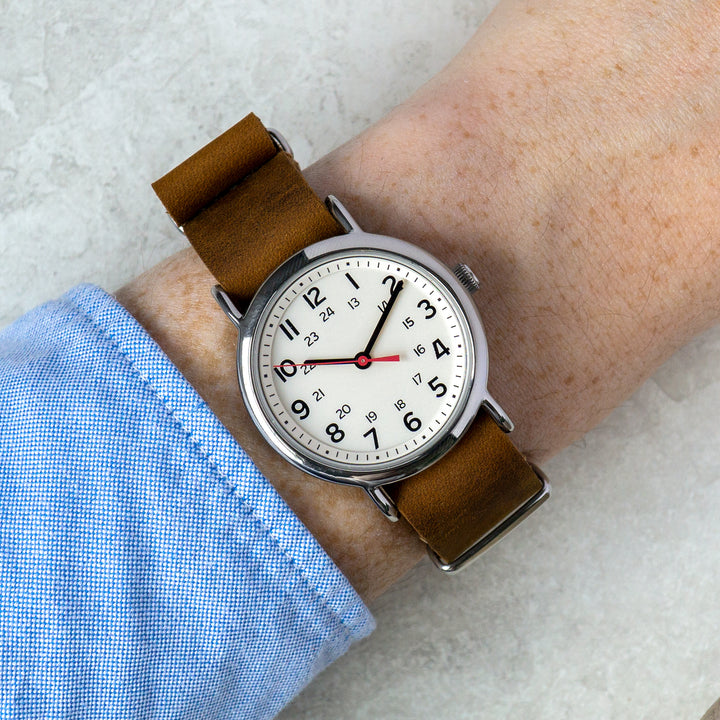 Wrist wearing a watch with a brown leather strap on a light background #color_dark-brown