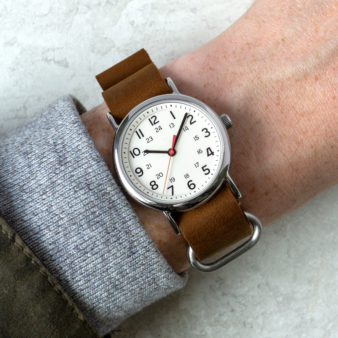 Wristwatch with brown leather strap on a wrist against a light background #color_dark-brown