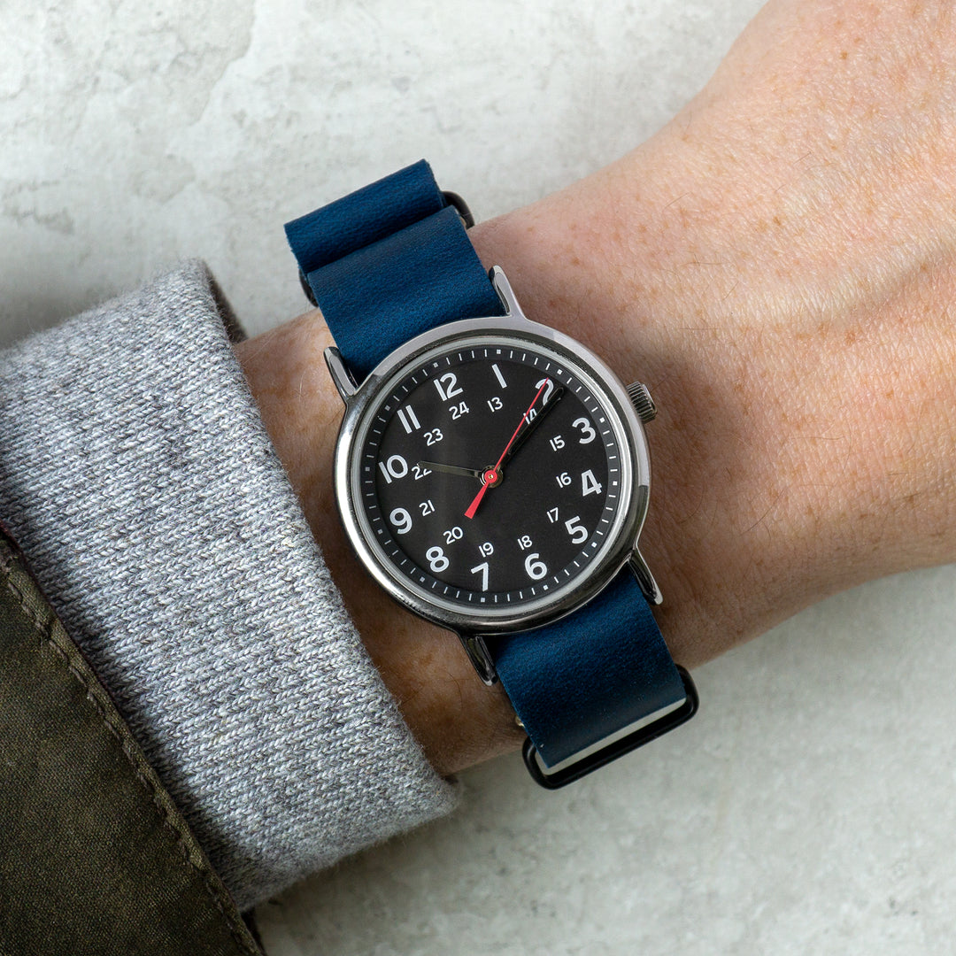 Wrist wearing a watch with a blue strap on a light background #color_navy-blue-pvd