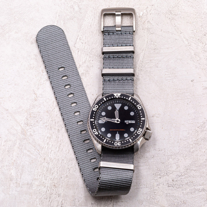 Wristwatch with gray strap and black dial on a light gray background #color_grey
