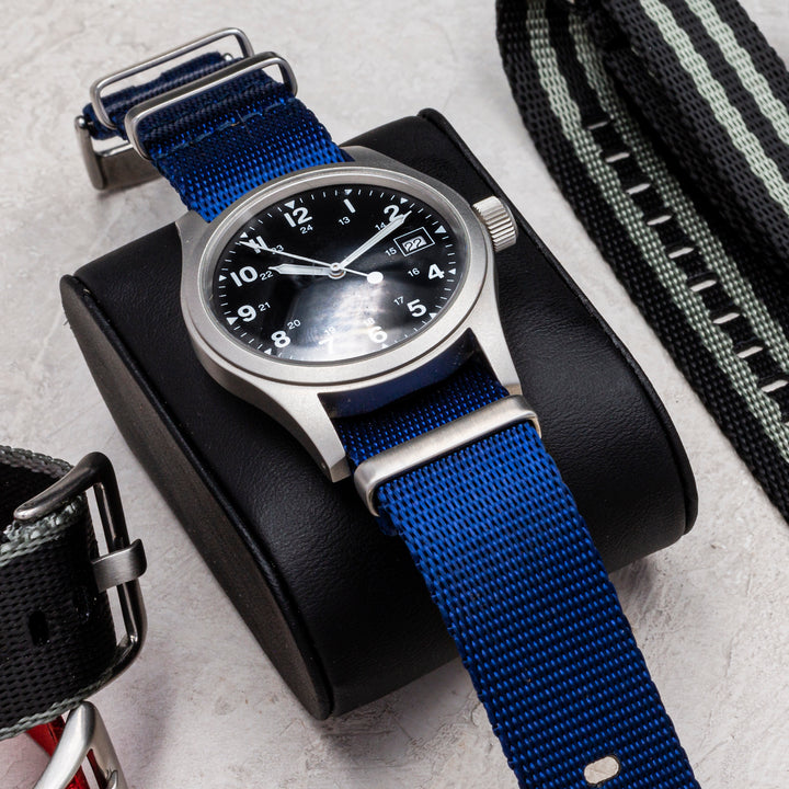 Watch with blue strap and black face on a light gray surface #color_navy-blue