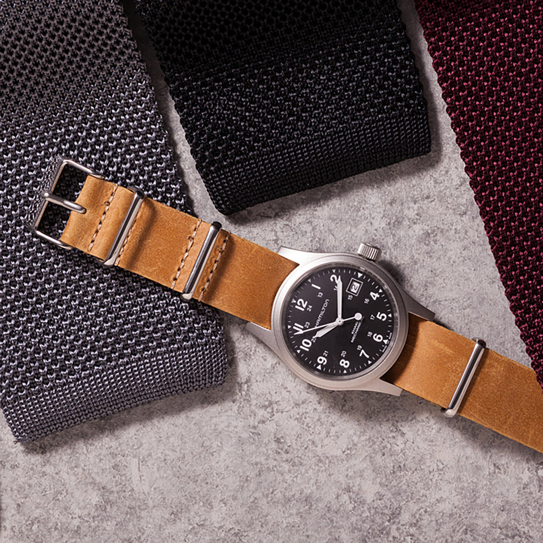 Watch with brown leather strap on a textured surface #color_sand