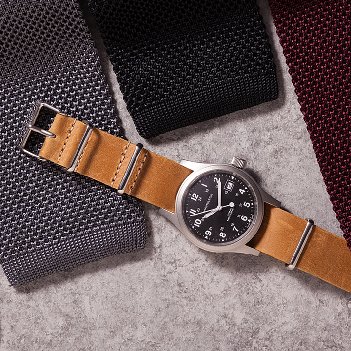Watch with brown leather strap on a textured surface #color_sand