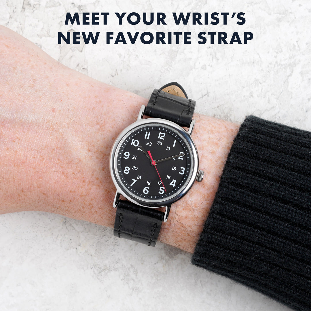 Person wearing a black wristwatch with a leather strap on a light background #color_black