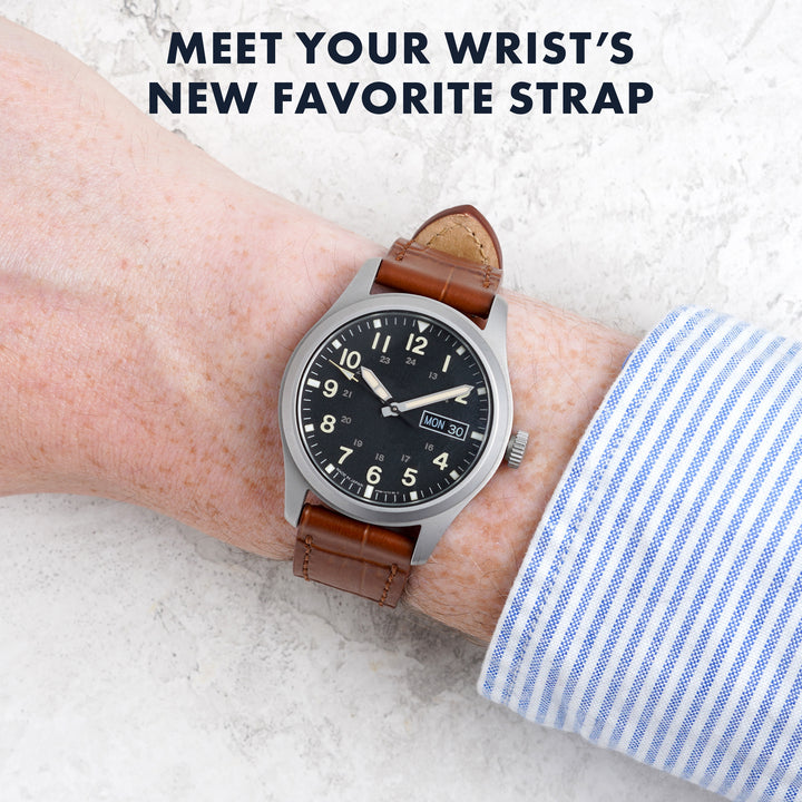 Watch with brown leather strap on wrist against a light background #color_tan