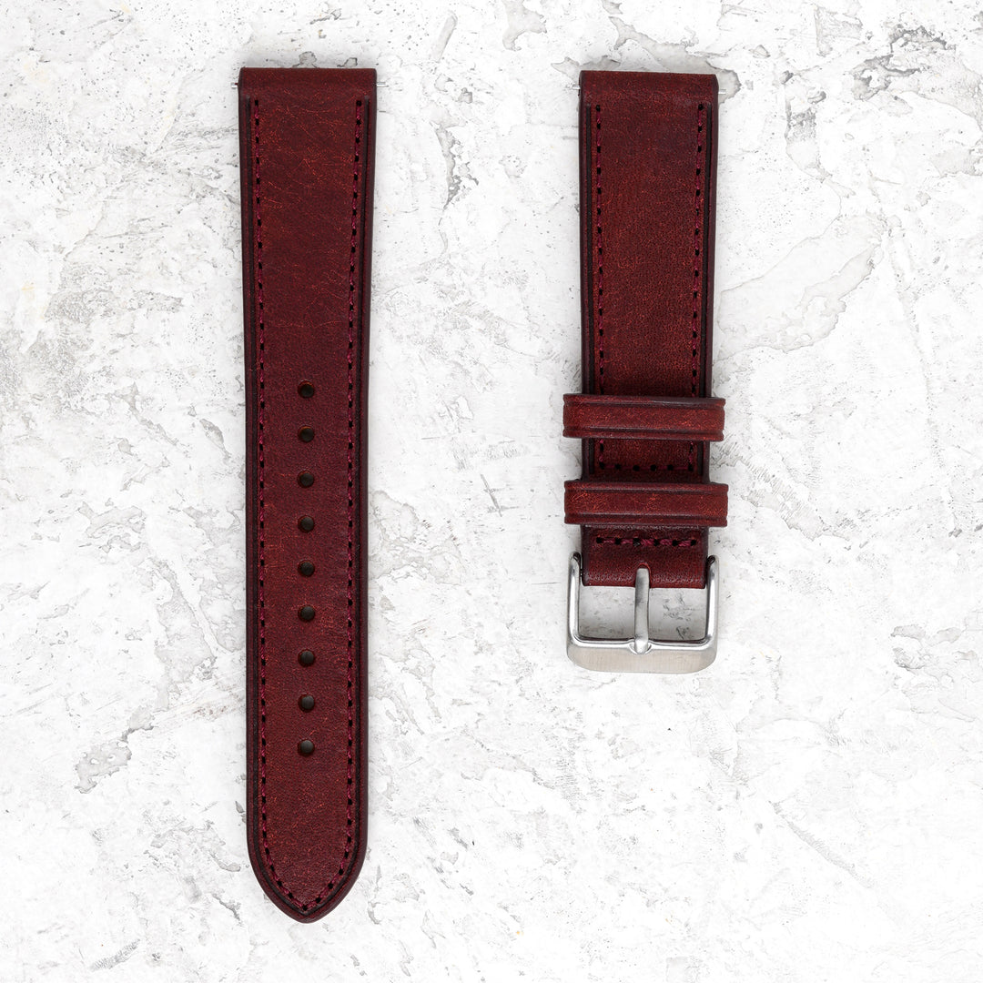 Brown leather watch strap with silver buckle on a textured white background #color_burgundy