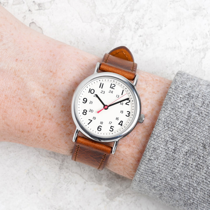 Wrist wearing a watch with a brown leather strap on a light background #color_rust