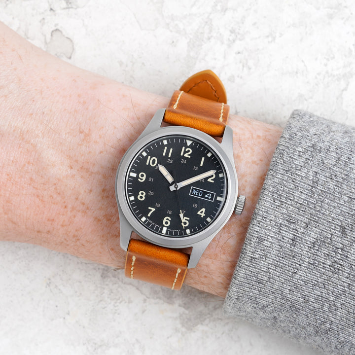 Wristwatch with brown leather strap on a wrist against a light background #color_yellow