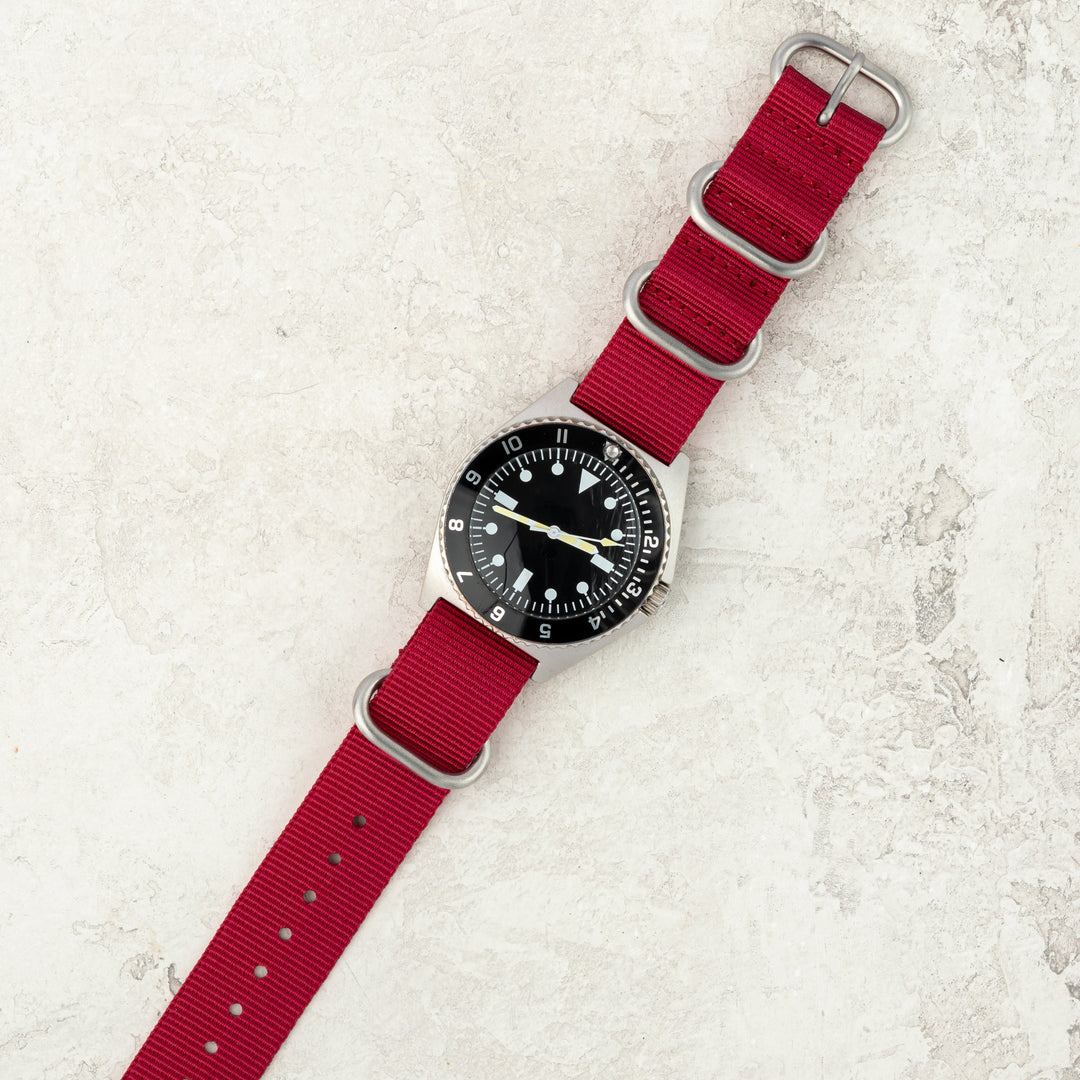 Watch with a red strap on a textured white surface #color_red