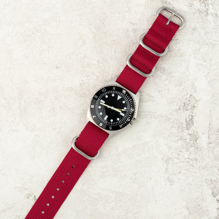 Watch with a red strap on a textured white surface #color_red