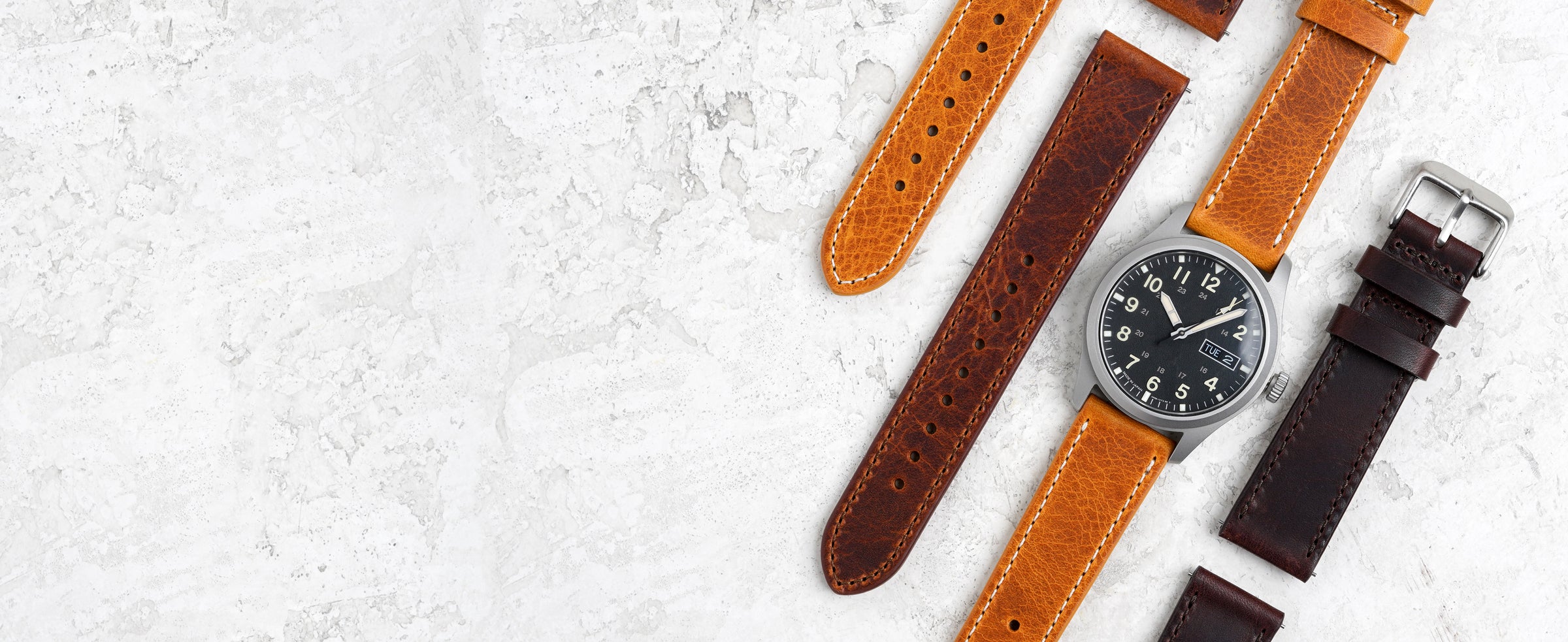 Watch with multiple leather straps on a textured white surface