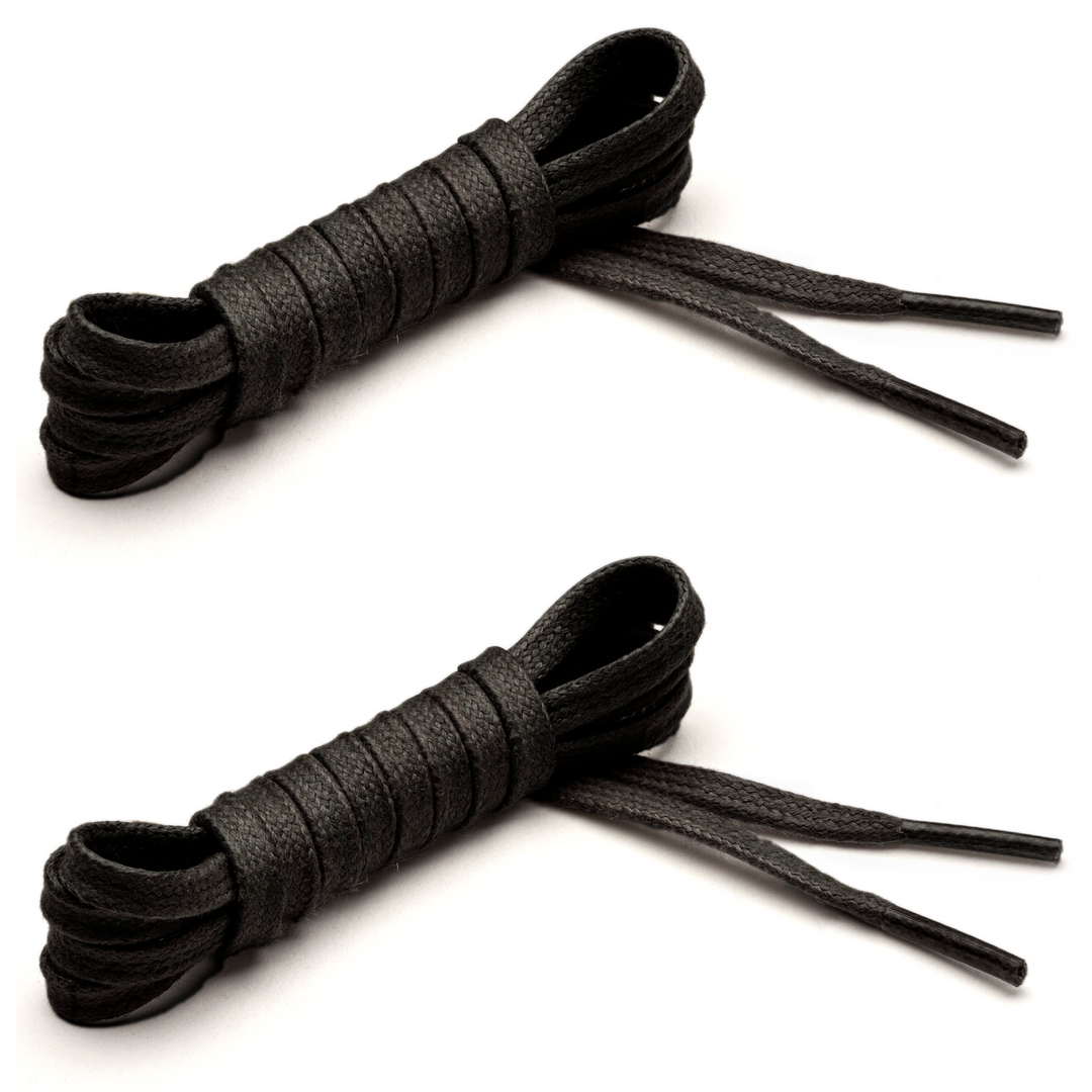 Two pairs of flat waxed cotton black shoelaces with clear aglets, coiled and placed side by side. #color_black